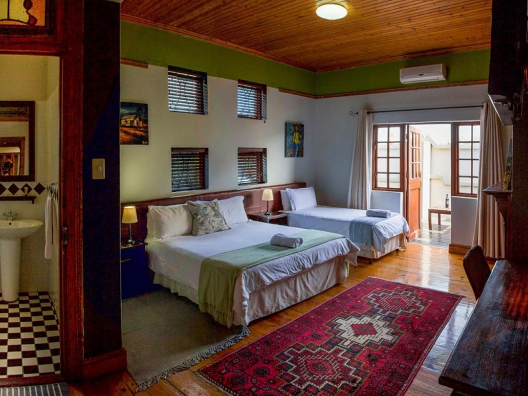 Twin beds with wooden ceiling, patterned rug, door opening to patio.