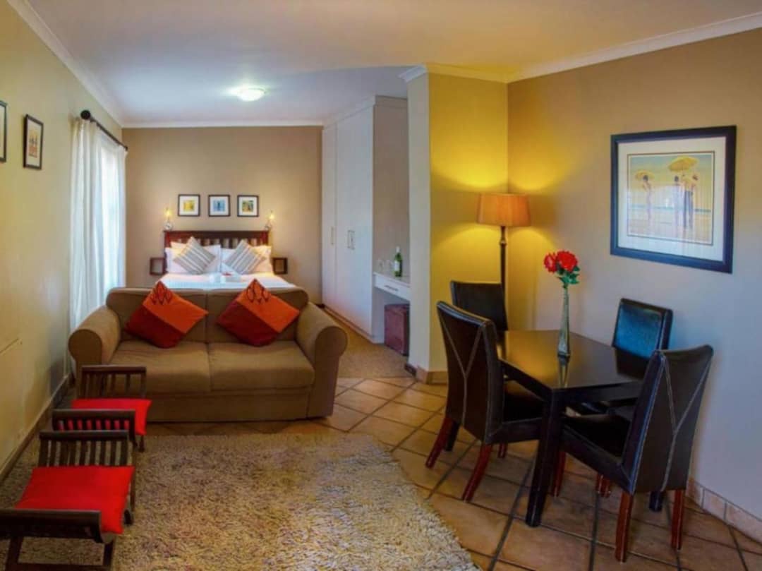 Studio room with bed, sofa, dining table and framed artwork.