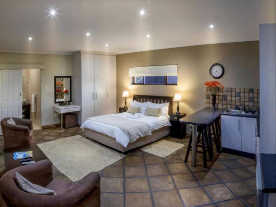 Studio room with bed, kitchenette, seating area and tiled flooring.