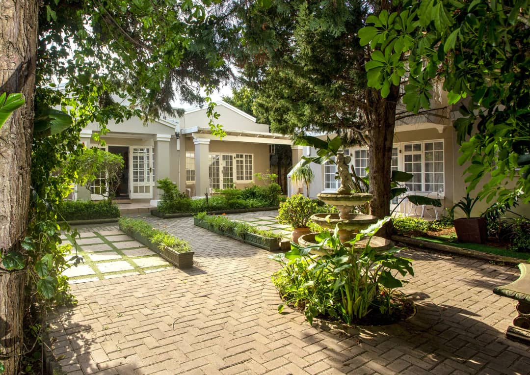 Paved courtyard with tiered stone fountain, gardens and shaded rooms.