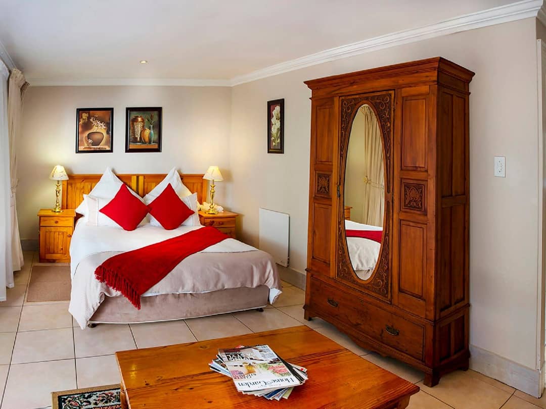 Bedroom with red accents, antique mirrored wardrobe, and bedside lamps.