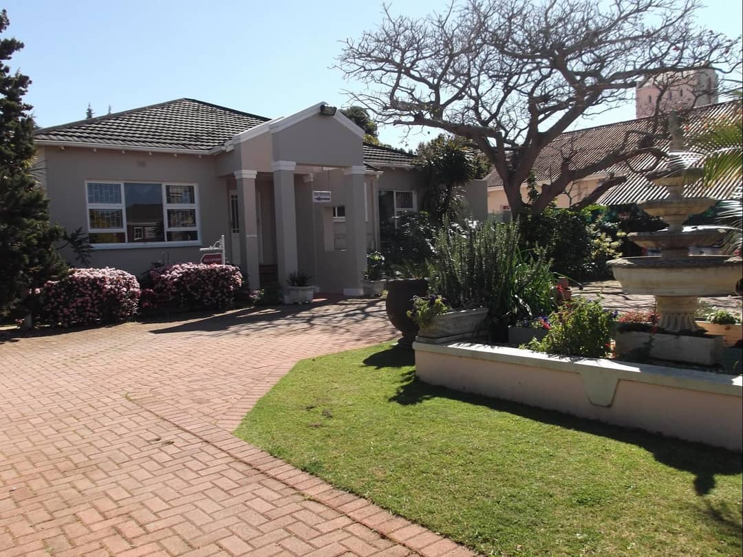 Entrance with reception sign, garden fountain and flowering shrubs
