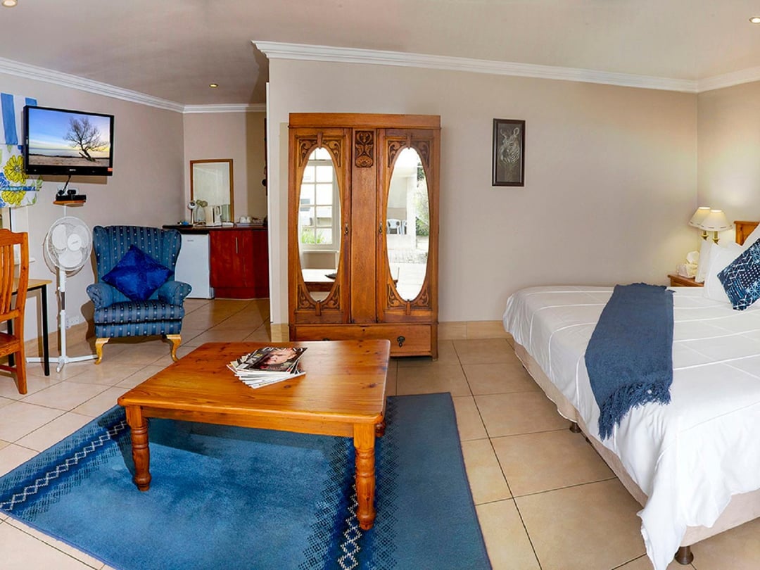 Spacious room with antique wardrobe, seating area, and double bed.